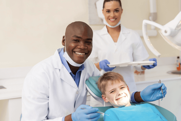 Black dentist smiling with kid in patient chair, huntsville al