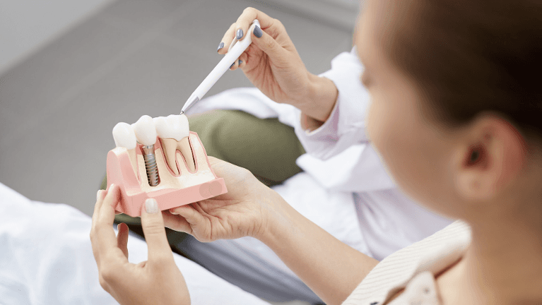 Dentist showing patient a mold of implant-retained dentures, huntsville al
