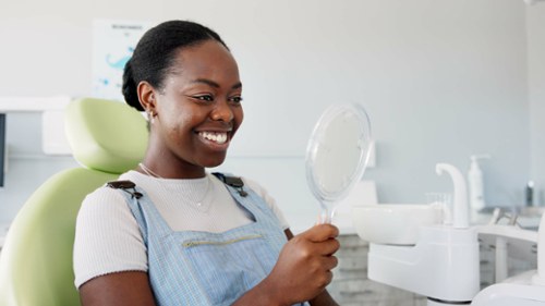 Black woman smiling into handheld mirror, huntsville al