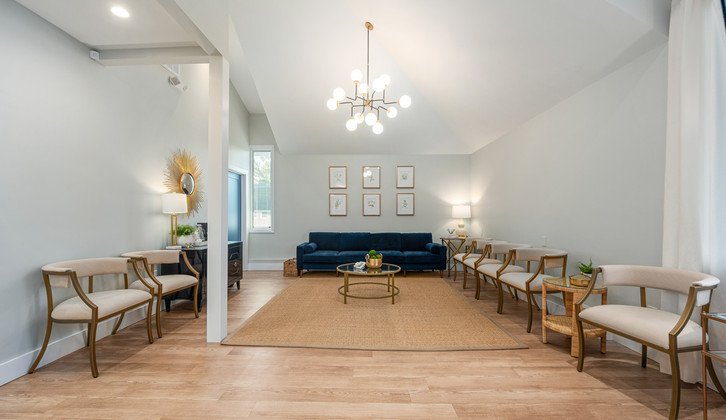 Twickenham Family Dentistry A wider view of the waiting room, showcasing a high ceiling, modern chandelier, and an inviting seating arrangement with beige and gold-accented chairs.